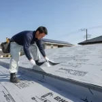 住宅の陸屋根で、専門的な道具を使い塩ビシート防水工事を施工する日本の職人。高額見積もりの一因となる専門工事の様子