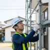 住宅の外壁塗装工事で、専門の職人が安全に足場を組み立てている様子