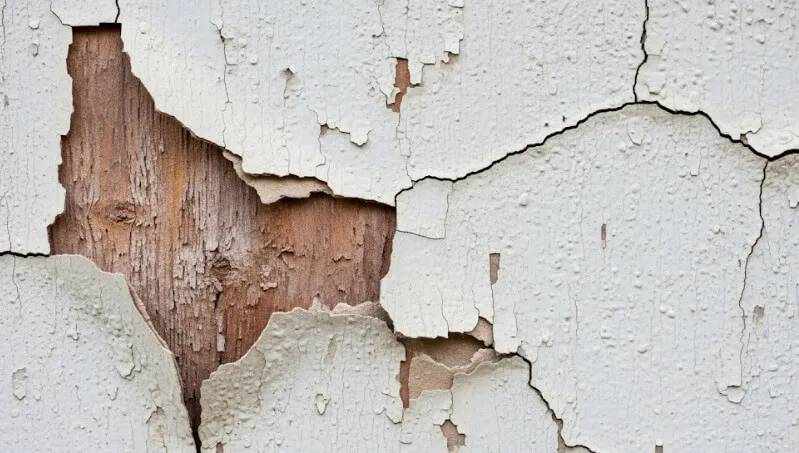 塗装が剥がれ、深刻なひび割れ(クラック)が入り下地が見えている外壁のクローズアップ写真