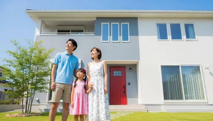 新しく塗装されたモダンな家の前で、満足そうに微笑むある日本の家族。