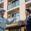 株式会社アップリメイクの専門スタッフ（作業員とスーツ姿の担当者）が、アパートの前で打ち合わせをしている。企業の専門性と信頼性を象徴している