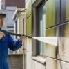 日本人の専門家が、カビやコケで汚れた外壁を高圧洗浄機を使い、パワフルに清掃している様子