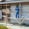 日本の住宅で外壁塗装の各工程（高圧洗浄、足場でのローラー塗装）が丁寧に行われている様子